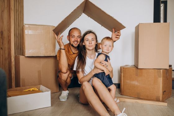 Une famille assise au sol, un carton au-dessus de la tête en guise de toit