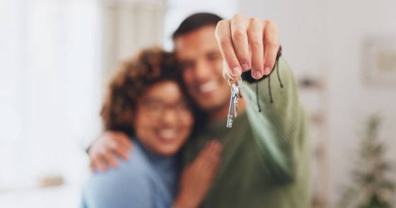 Main, clés et un couple de propriétaires fiers de leur investissement ou achat immobilier