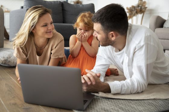 Un couple et leur fille devant un ordinateur portable