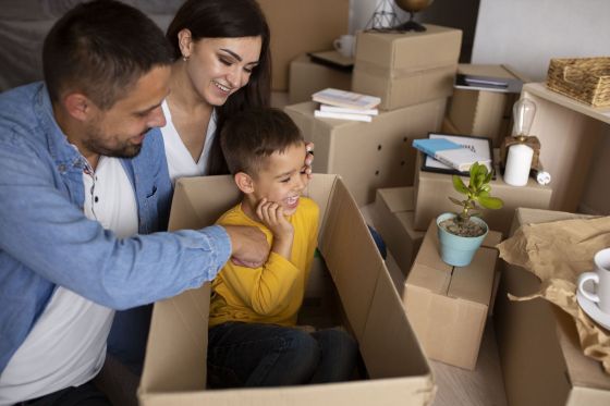 Une famille assise dans un carton lors d’un déménagement.