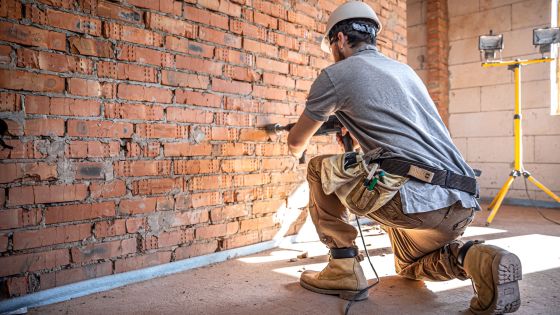 Ouvrier sur un chantier perçant un mur de briques
