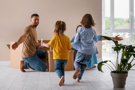 Deux enfants courent vers leurs parents dans un salon avec des cartons